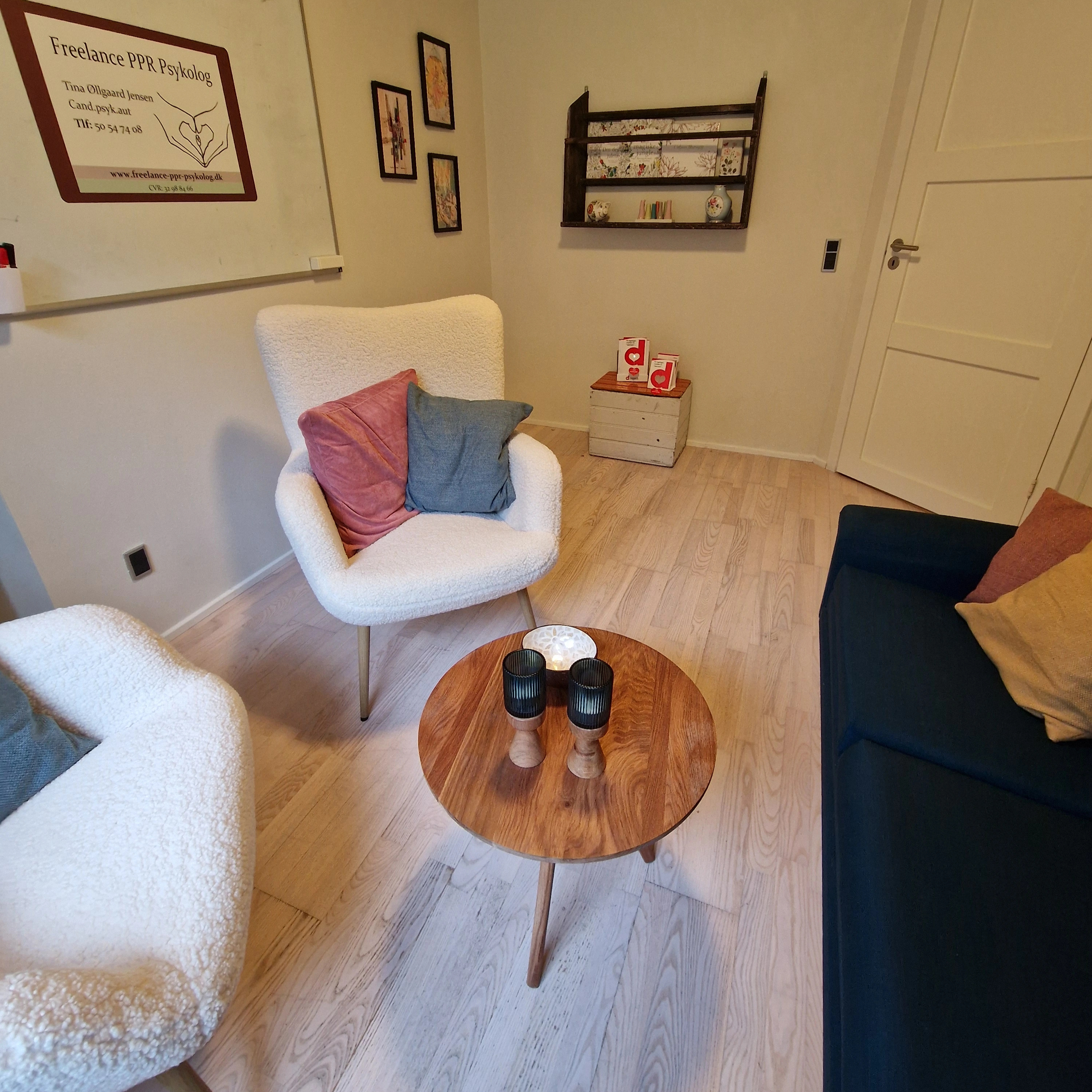 Billede af samtalerummet, hvor der står en blå sofa og to hvide lænestole. Der er udsigt ud til hestefolden.