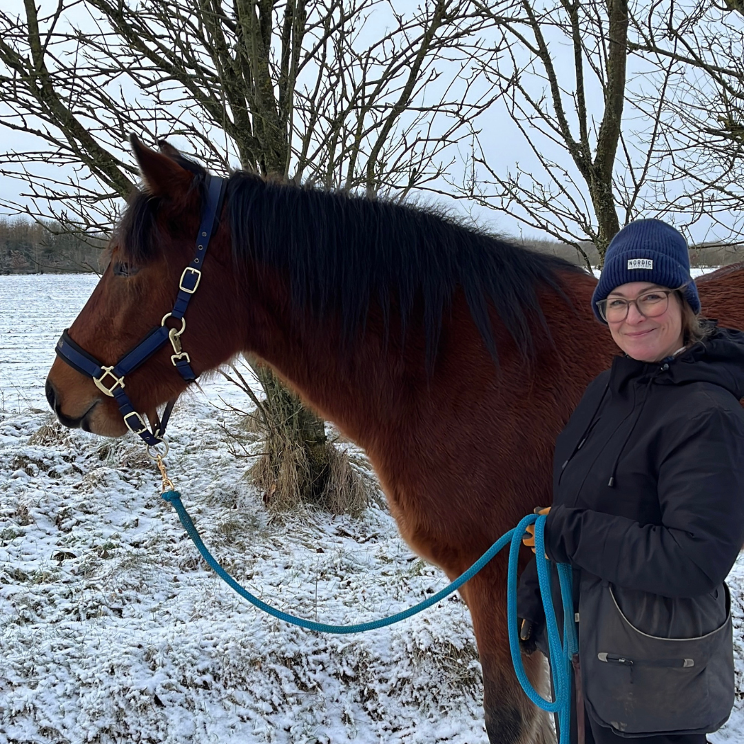 Tina, der står med hendes unghest, Phønix. Tina smiler til kameraet og Phønix kigger fremad.